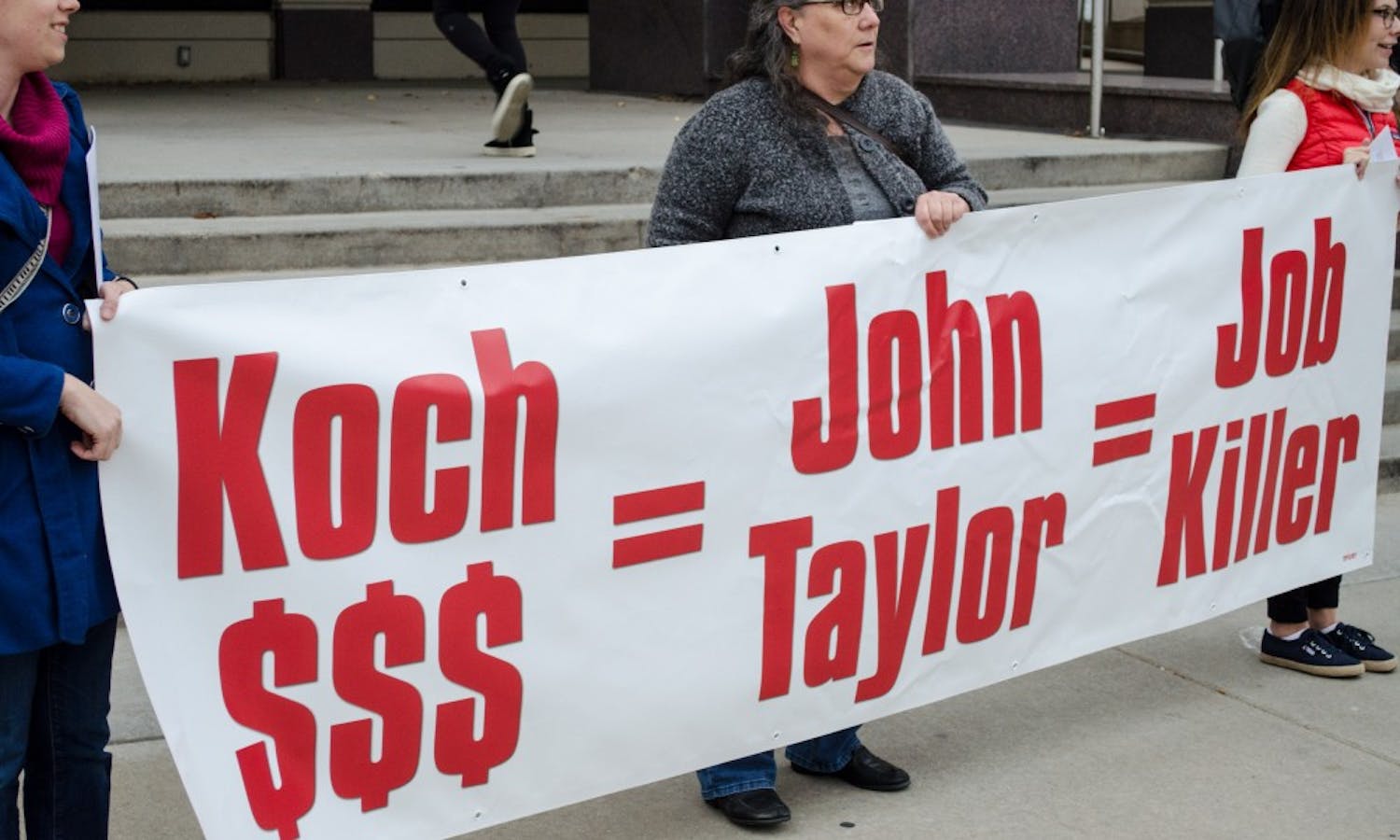 UW-Madison students and community members&nbsp;held a banner denouncing potential Fed Chair nominee John Taylor.