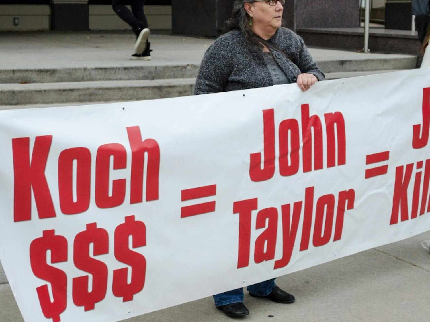 UW-Madison students and community members&nbsp;held a banner denouncing potential Fed Chair nominee John Taylor.