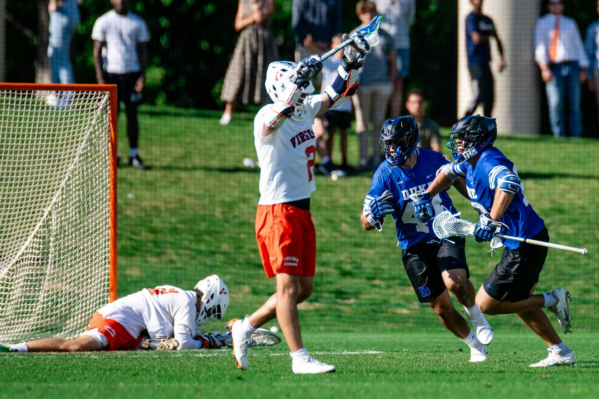 Virginia goalie Matthew Nunes lies frozen on the ground, attackman Thomas Mencke raises his stick in the air helplessly, and victorious Duke players sprint away.