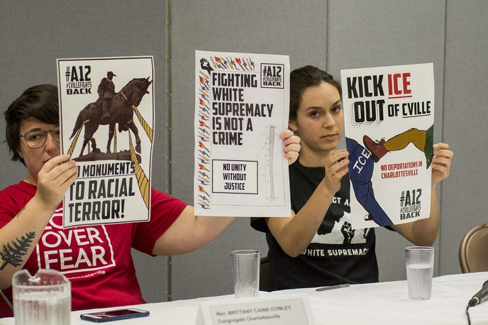 Red. Brittany Caine-Conley of Congregate Charlottesville and Sophie Schectman, an organizer with U.VA. Students United, hold up posters highlighting local activist efforts.&nbsp;