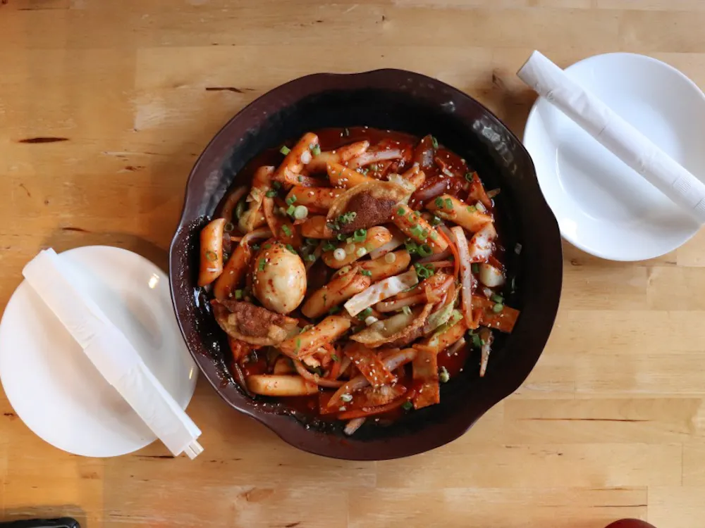 Tteokbokki is a Korean dish that has stir-fried rice cakes, typically served spicy when mixed with gochujang, a type of Korean chili paste. 