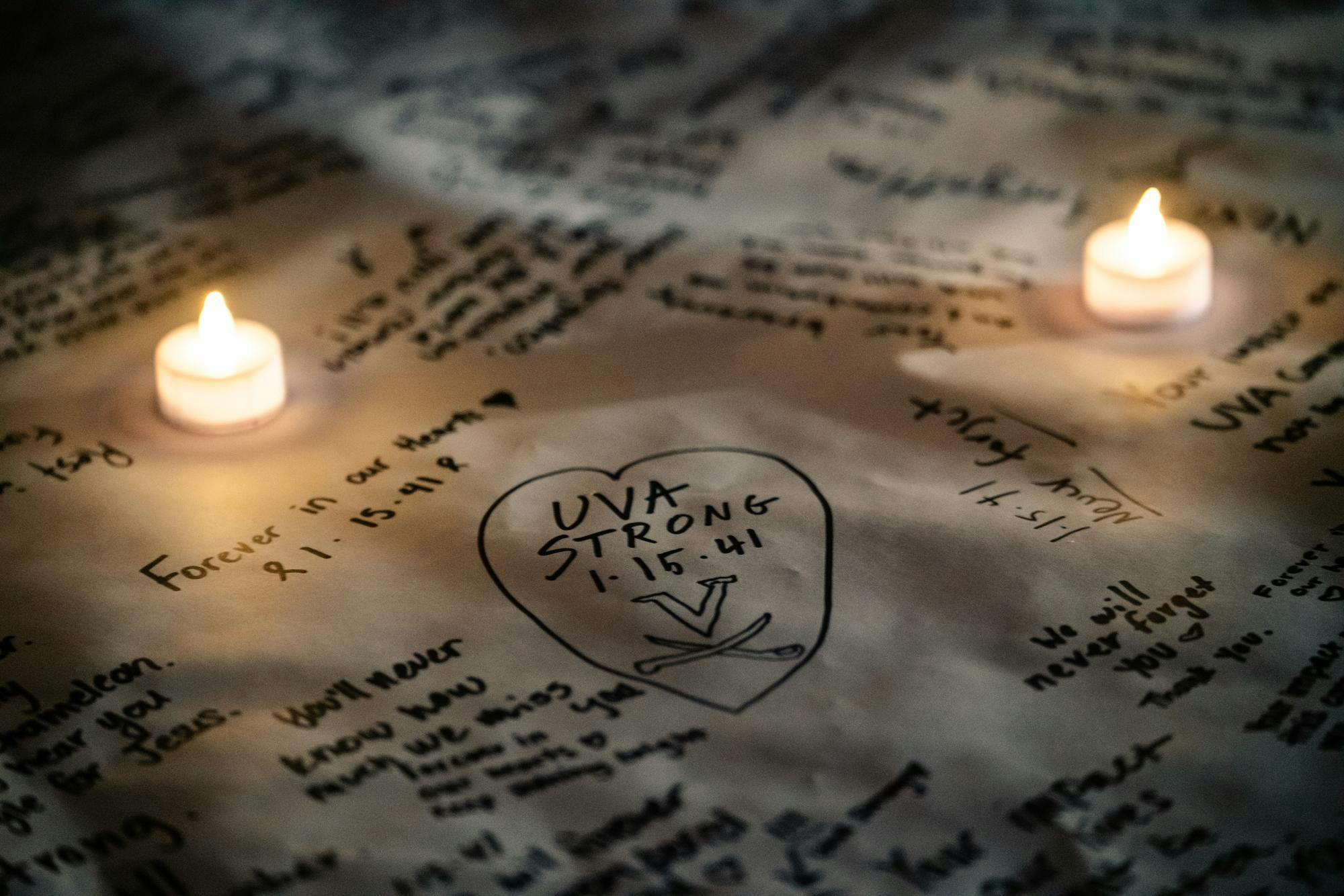 A banner memorializing Lavel Davis Jr., D'Sean Perry and Devin Chandler — the victims of the Nov. 13, 2022 shooting — illuminated in candlelight Nov. 13, 2024.