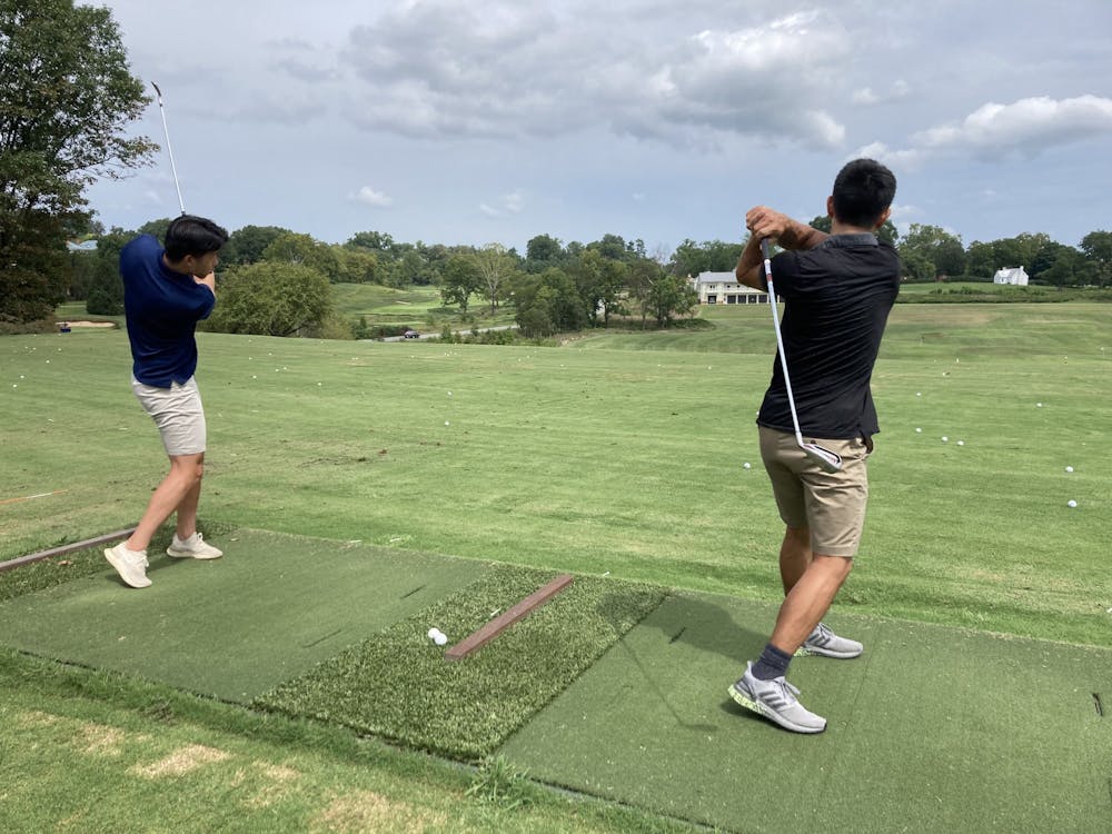 Fourth-year Engineering student Tae Chang and fourth-year College student Eric Su practice their swings on the driving range during Golf class.