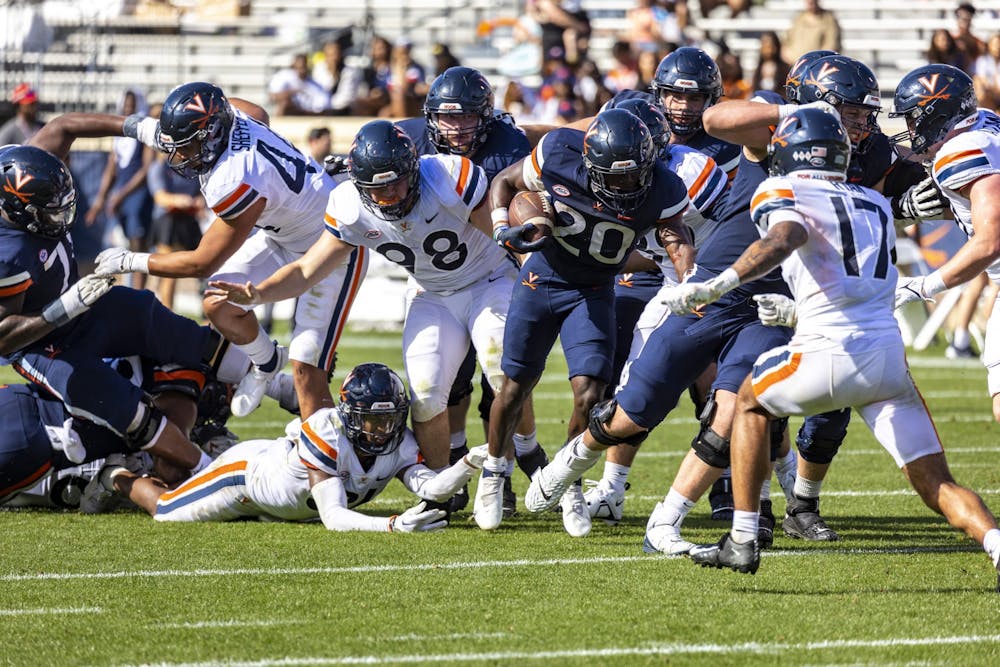 <p>Virginia's offensive line creates a hole for sophomore running back Xavier Brown at the team's spring game.</p>