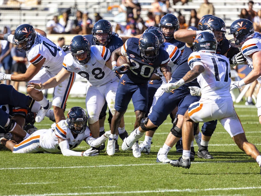 Virginia's offensive line creates a hole for sophomore running back Xavier Brown at the team's spring game.