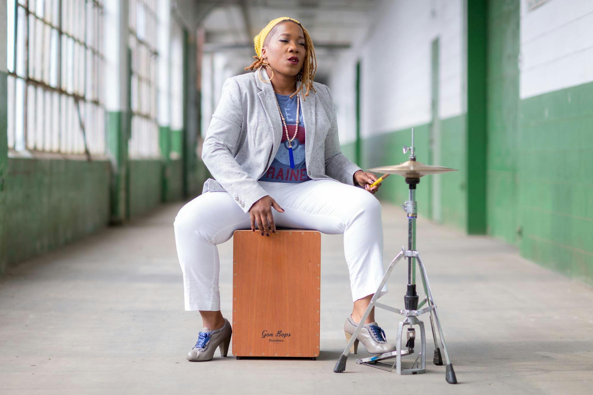 Instead of having separate drums for her kick and snare, Armstrong creates both sounds by slapping a cajon, a small wooden box-drum on which she sits.