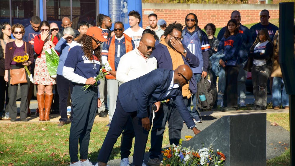Community members watch as friends and family lay flowers at the memorial of D'Sean Perry, Lavel Davis Jr. and Devin Chandler Nov. 13, 2025. Perry, Davis and Chandler were three University students who were killed in a shooting Nov. 13, 2022.