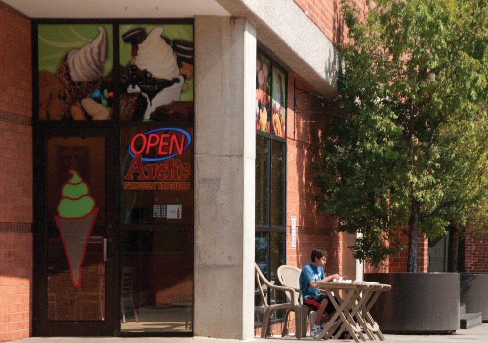 	A student enjoys some frozen yogurt while studying. 