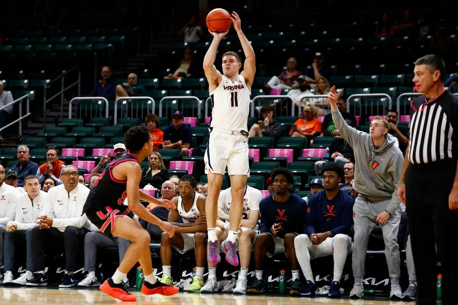 Isaac McKneely, watched on by banks of empty seats, rises for a three-pointer.