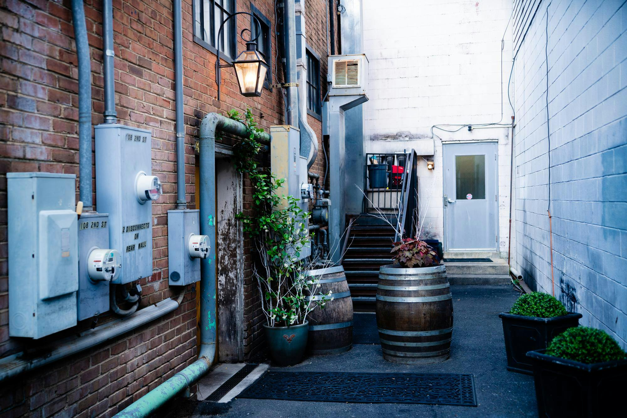 The restaurant itself hides behind a wooden barn door, and the only signage is a large, glowing lantern hanging above it, illuminating the otherwise onyx street.