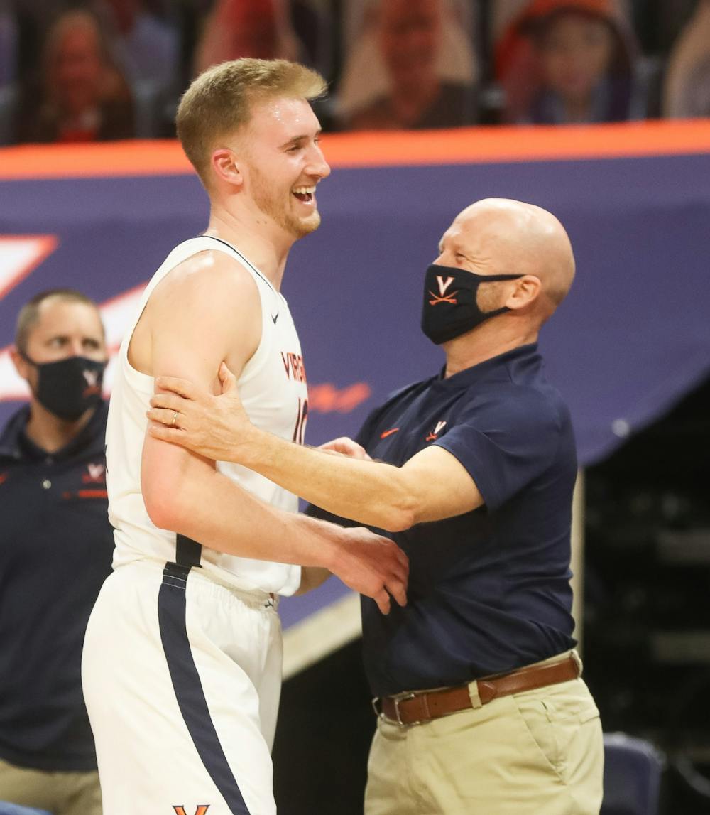 <p>Virginia senior forward Sam Hauser celebrates with assistant coach Brad Soderberg after coming off the court late in the game.</p>