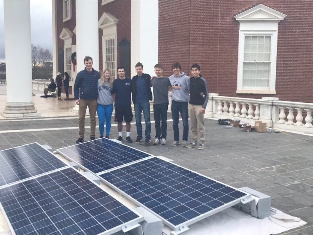 <p>Erik Toor, leader of the Lighting of the Lawn solar energy initiative, stands with his team from Charlottesville Solar Project next to their solar panels on the Rotunda</p>