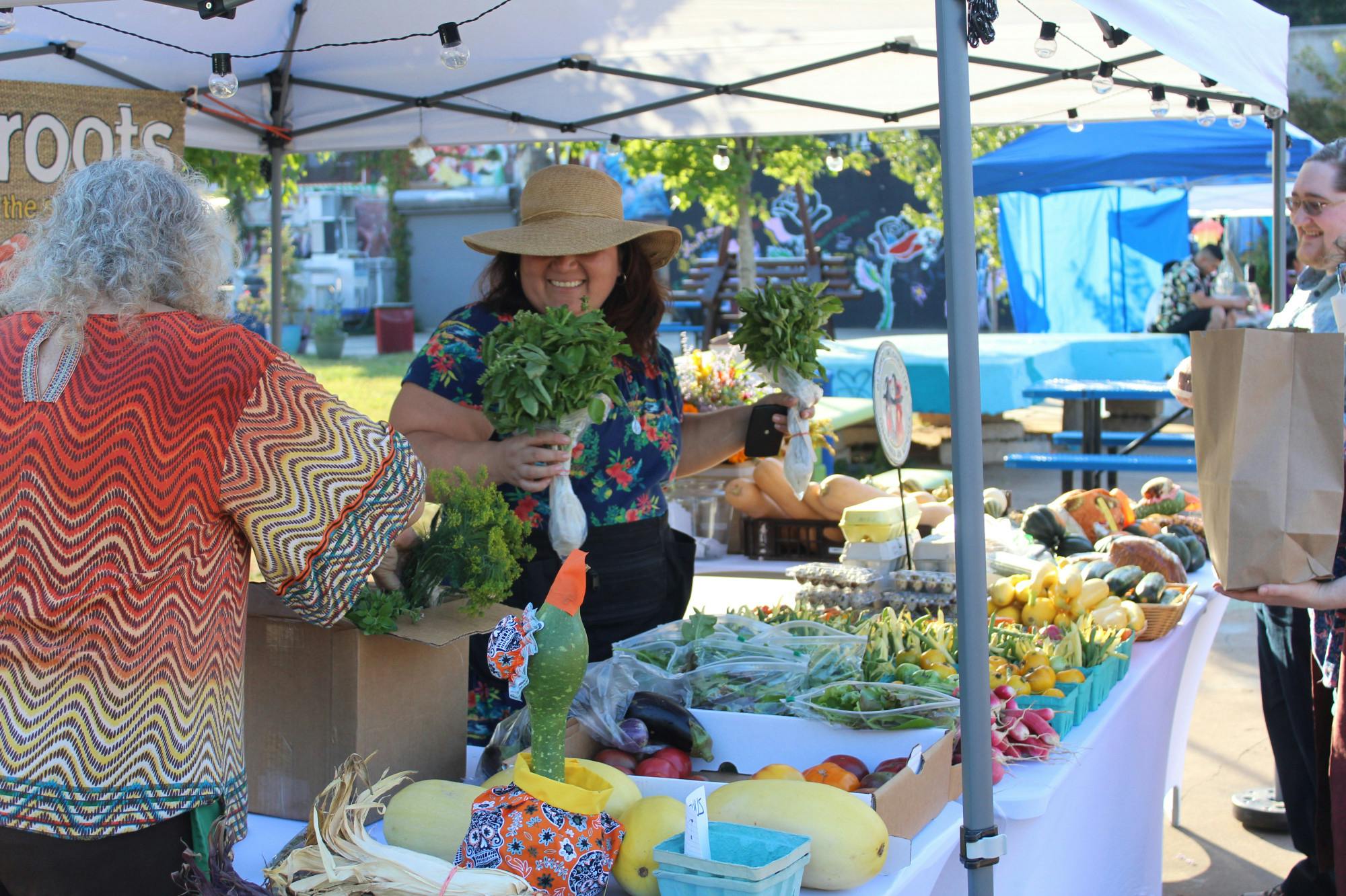 Strings of fairy lights twinkle over an open patio dotted with booths where vendors sell stickers, fiber art, woodwork, soaps and handmade jewelry. 
