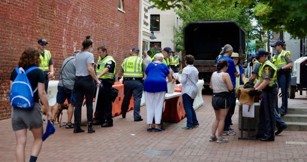 <p>Law enforcement personnel search peoples' bags at a security access checkpoint established at Third Street on the south side of the Downtown Mall.&nbsp;</p>