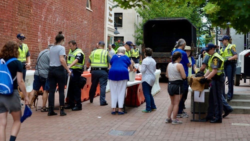 Law enforcement personnel search peoples' bags at a security access checkpoint established at Third Street on the south side of the Downtown Mall. 