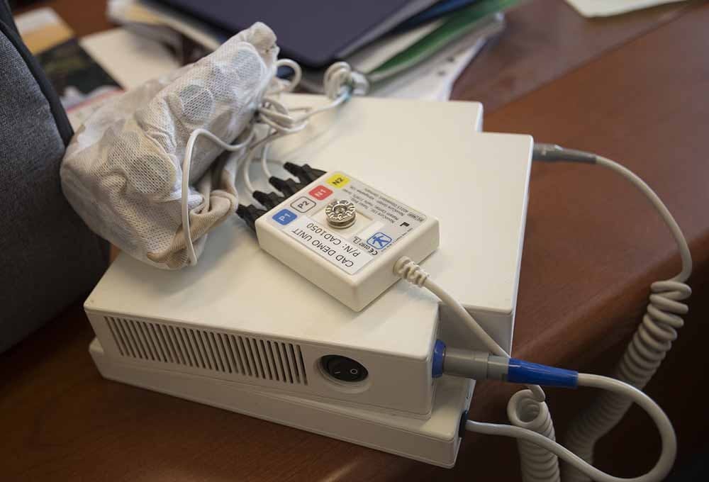 The Novocure device consists of a skull cap, shown folded up, and a machine that emits a low voltage electrical field through it, breaking up the threads that allow brain tumors to grow and spread.