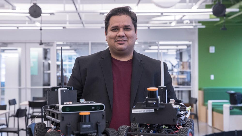 Madhur Behl — assistant professor of computer science, engineering systems and environment — stands behind two model F1/10 cars.