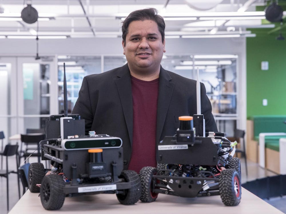 Madhur Behl — assistant professor of computer science, engineering systems and environment — stands behind two model F1/10 cars.