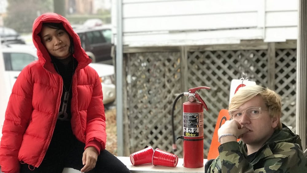 Fourth-year College student Lona Manik wears a red puffer coat from American Eagle Outfitters and third-year College student Ian Ware wears a taupe faux-fur coat from Urban Outfitters.