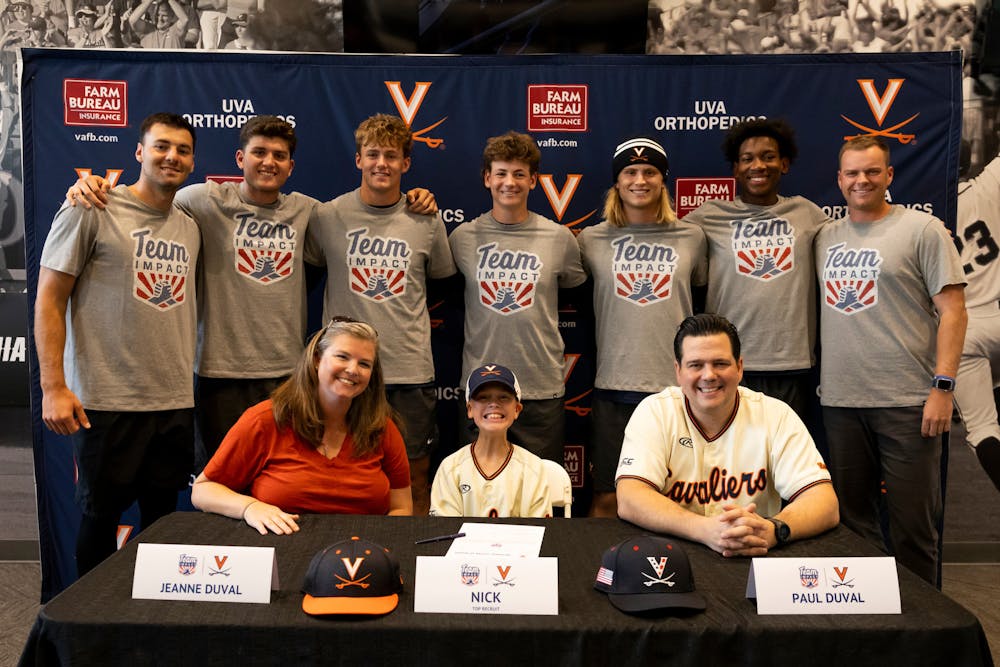 <p>Duval poses for a photo with his parents and members of the Virginia baseball program.</p>