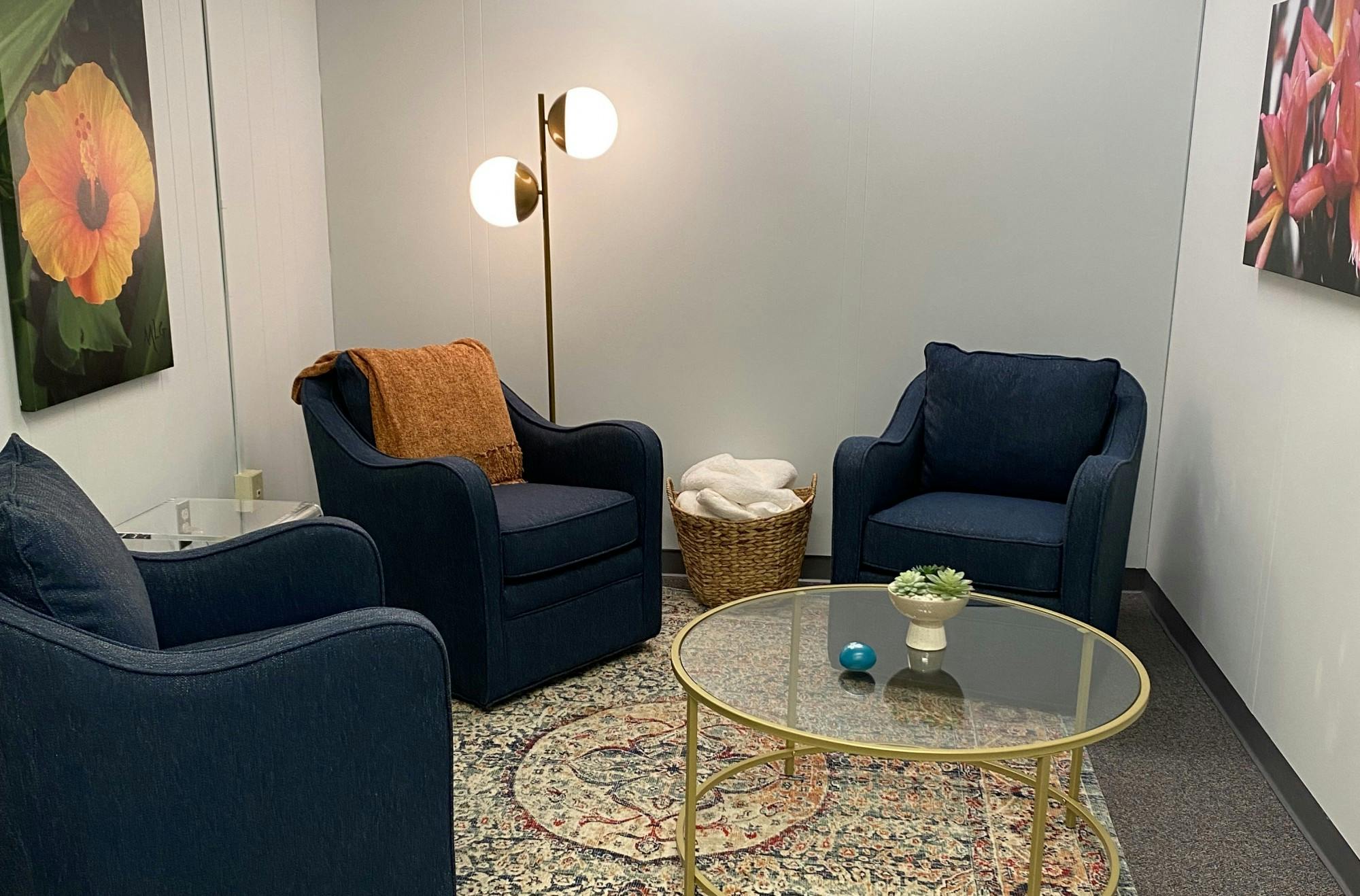 Comfortable chairs and blankets are placed around a simple coffee table topped with a plant and a stress ball.