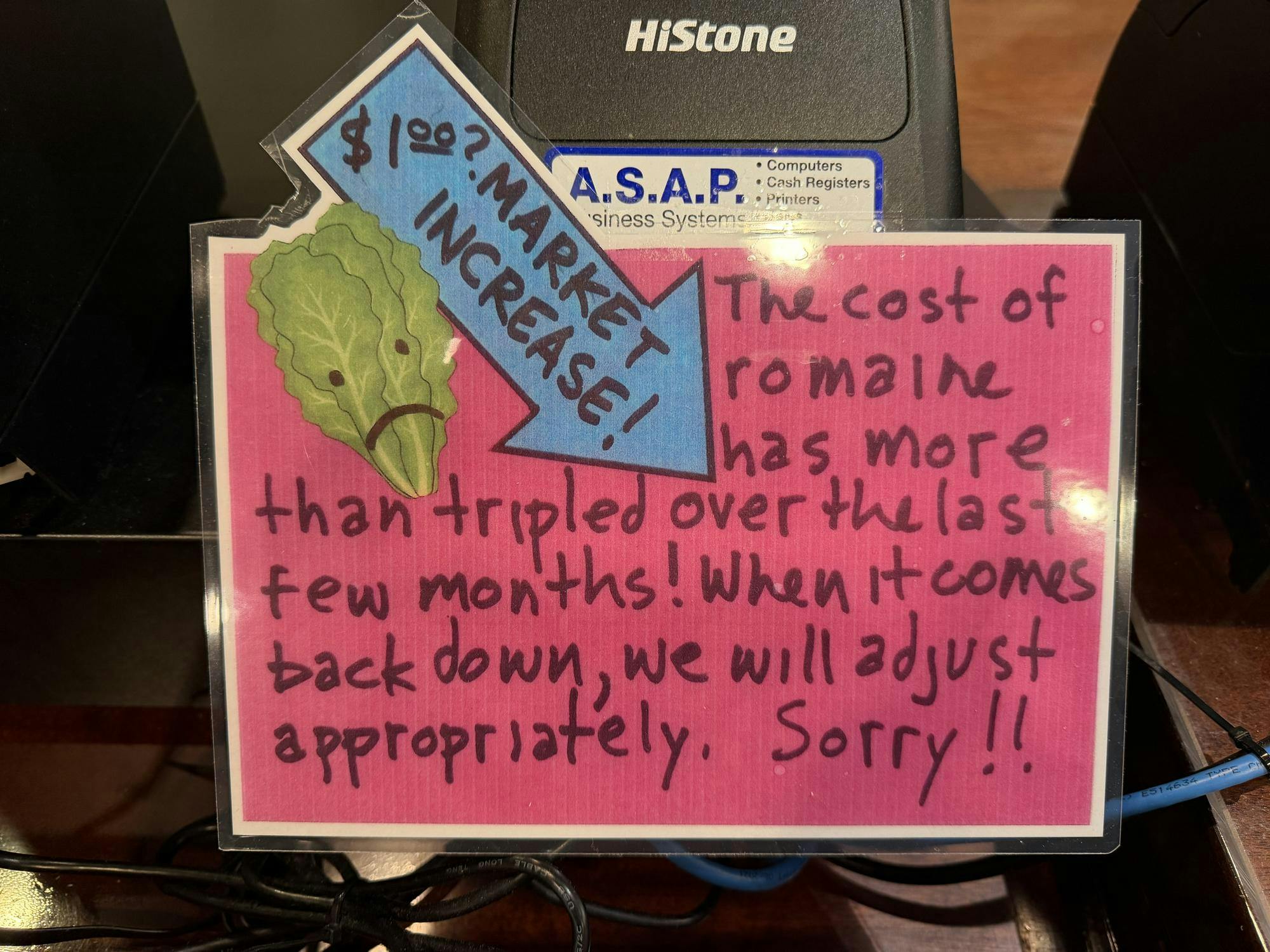 A sign at Bodo's Bagels, informing customers of a $1.00 surcharge for romaine lettuce, seen Nov. 11, 2025.