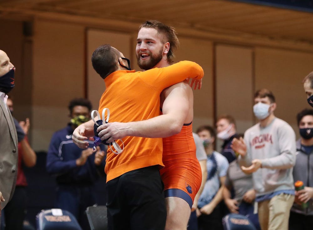 <p>Sophomore Quinn Miller celebrates with Coach Steve Garland after earning a major decision victory to give Virginia the win.</p>
