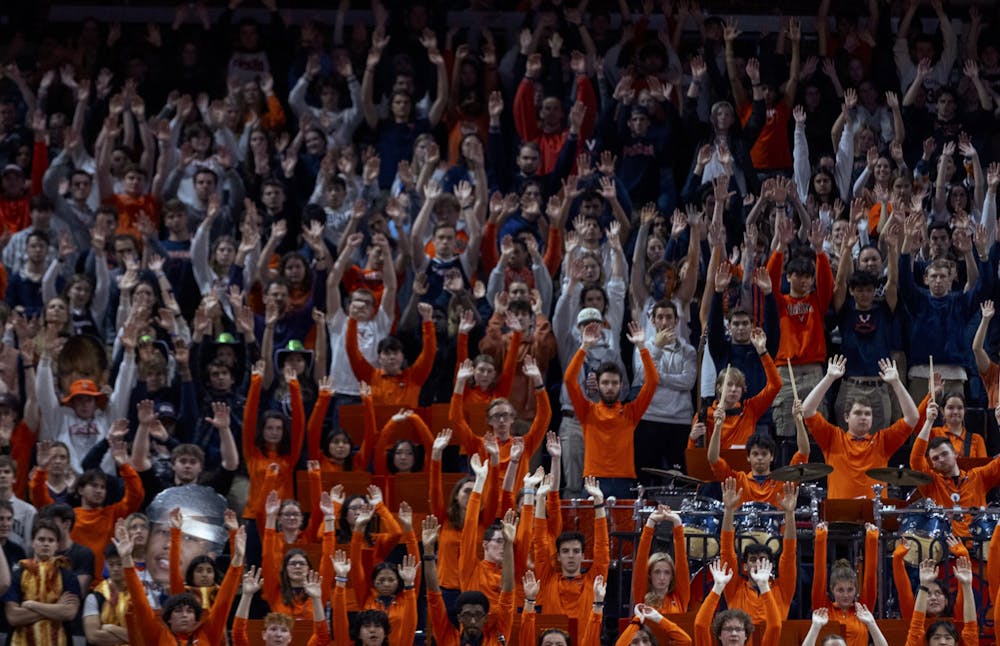 Virginia fans raise their arms as a Cavalier attempts a free throw.