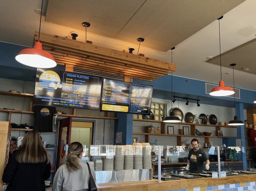 The blue and yellow tiled bar is used to take orders and pack food, with ambient orange lights hanging above and glass dividers that allow patrons to watch their meals being made. 