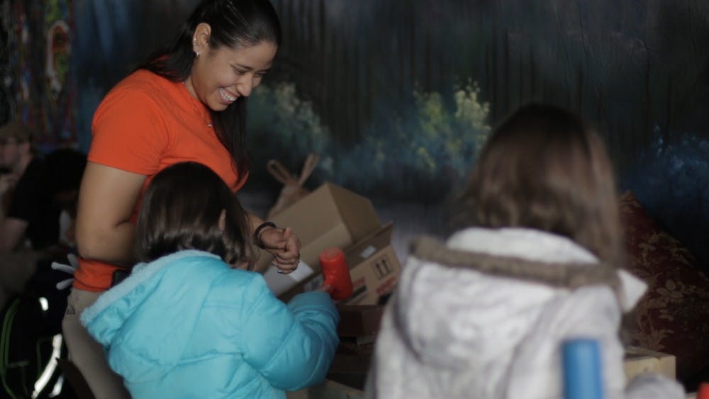 Historic Mason Daisy Maine guides two young girls through the bricklaying process.