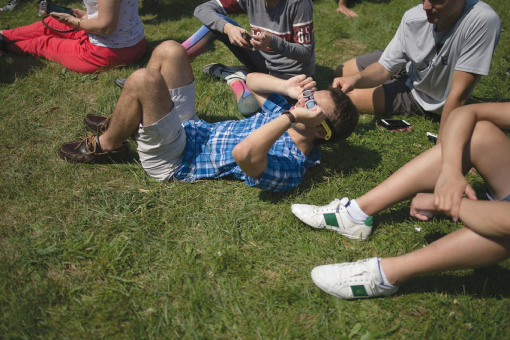 A Cornell student marvels at the solar eclipse on Monday afternoon as he relaxes on the grass.
