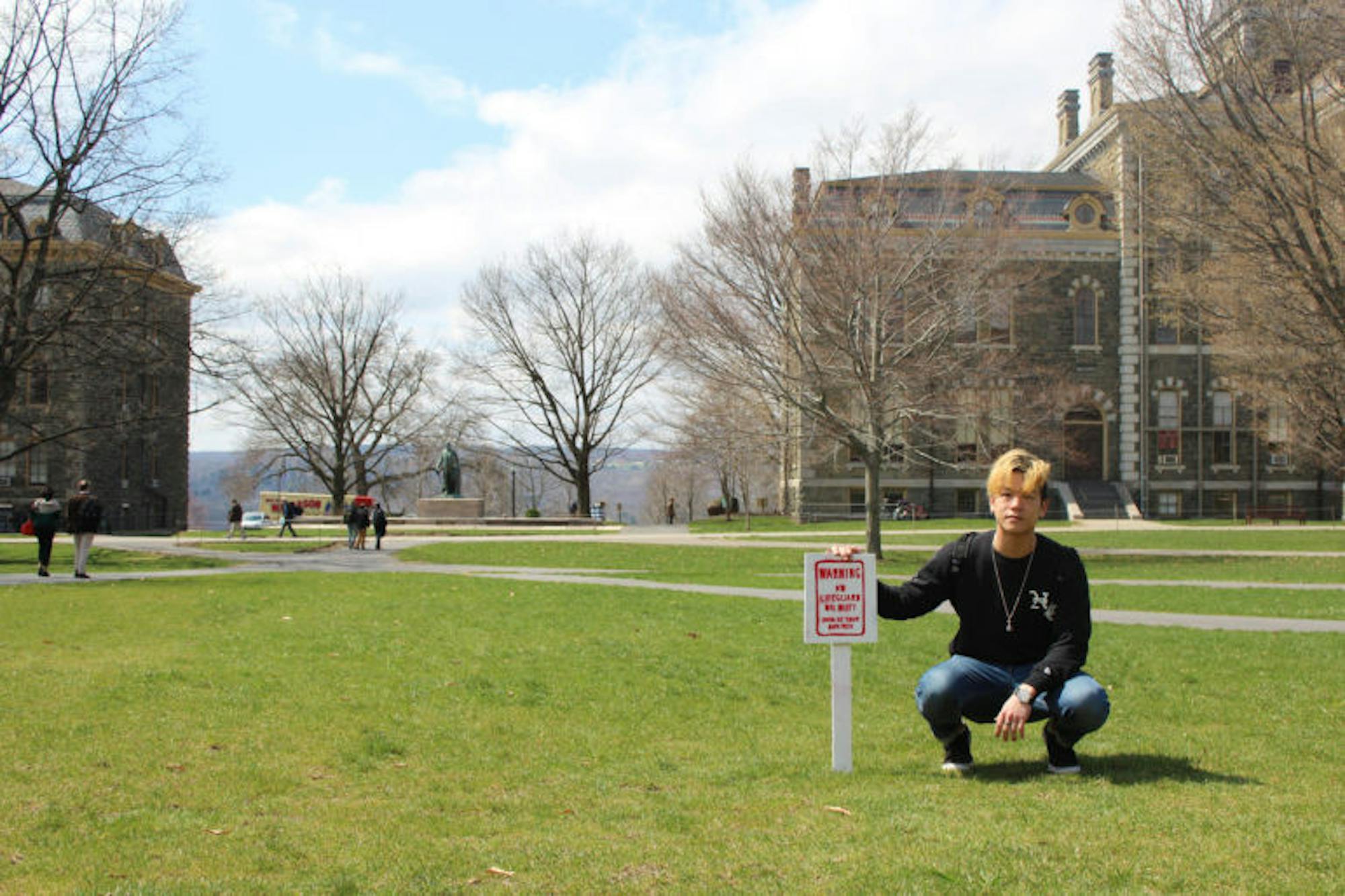 Daniel Seung Hwan Lee '20 crouches next to his art installation, the