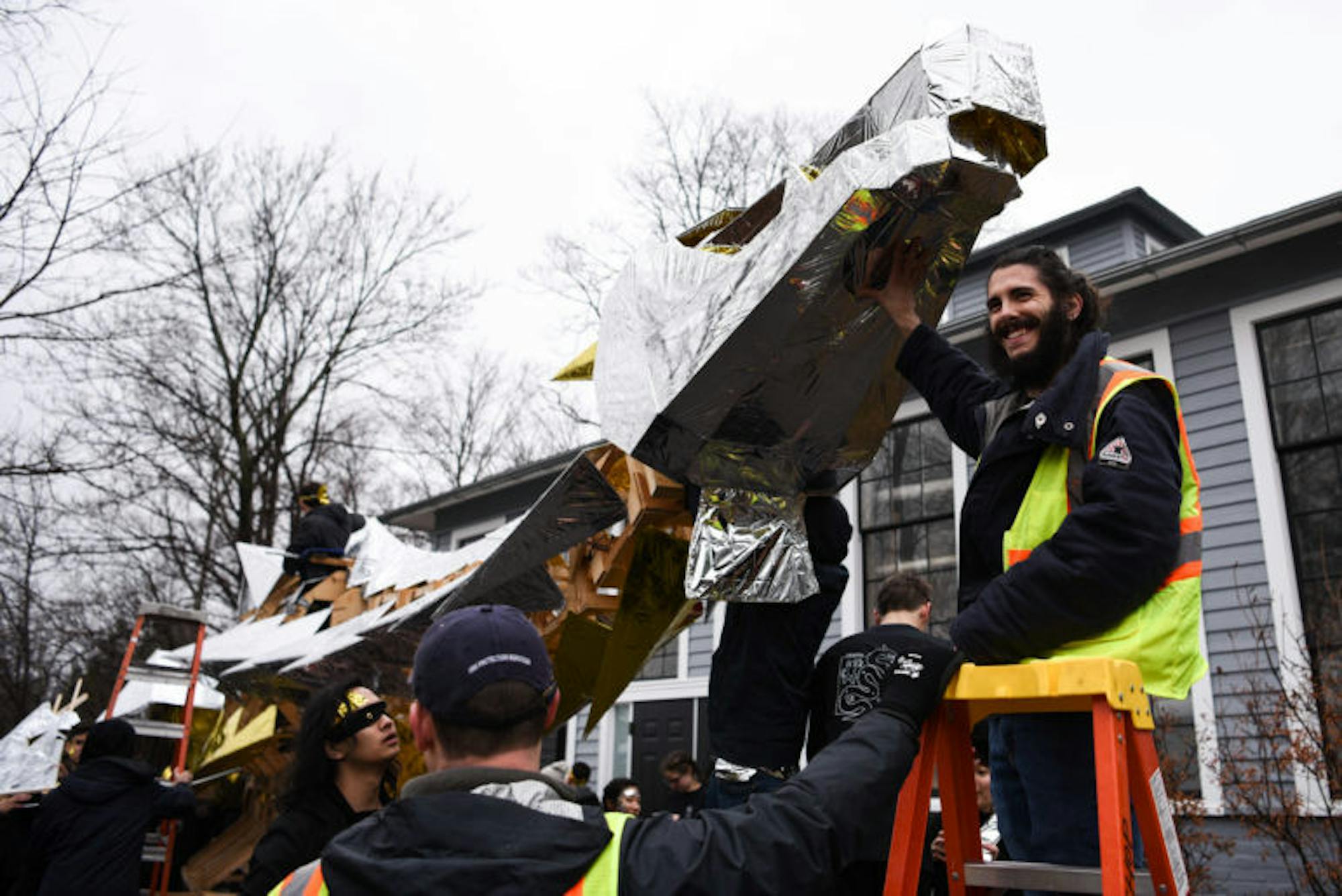 A security worker holds up the dragon’s head as students attach it to the neck.