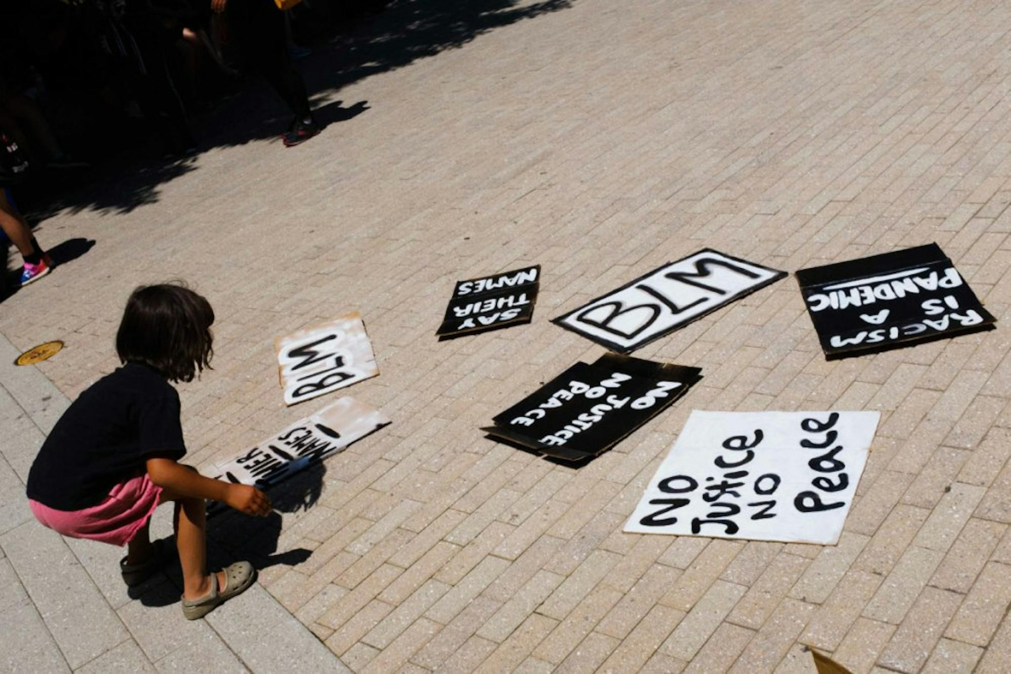 A child grabs a hand-painted sign at the Uplift and Speak Out! rally in the Ithaca Commons on Friday, June 5. Black and brown women organized the event, with the support of Black Lives Matter Ithaca and Showing Up for Racial Justice. (Michael Suguitan / Sun Staff Photographer).