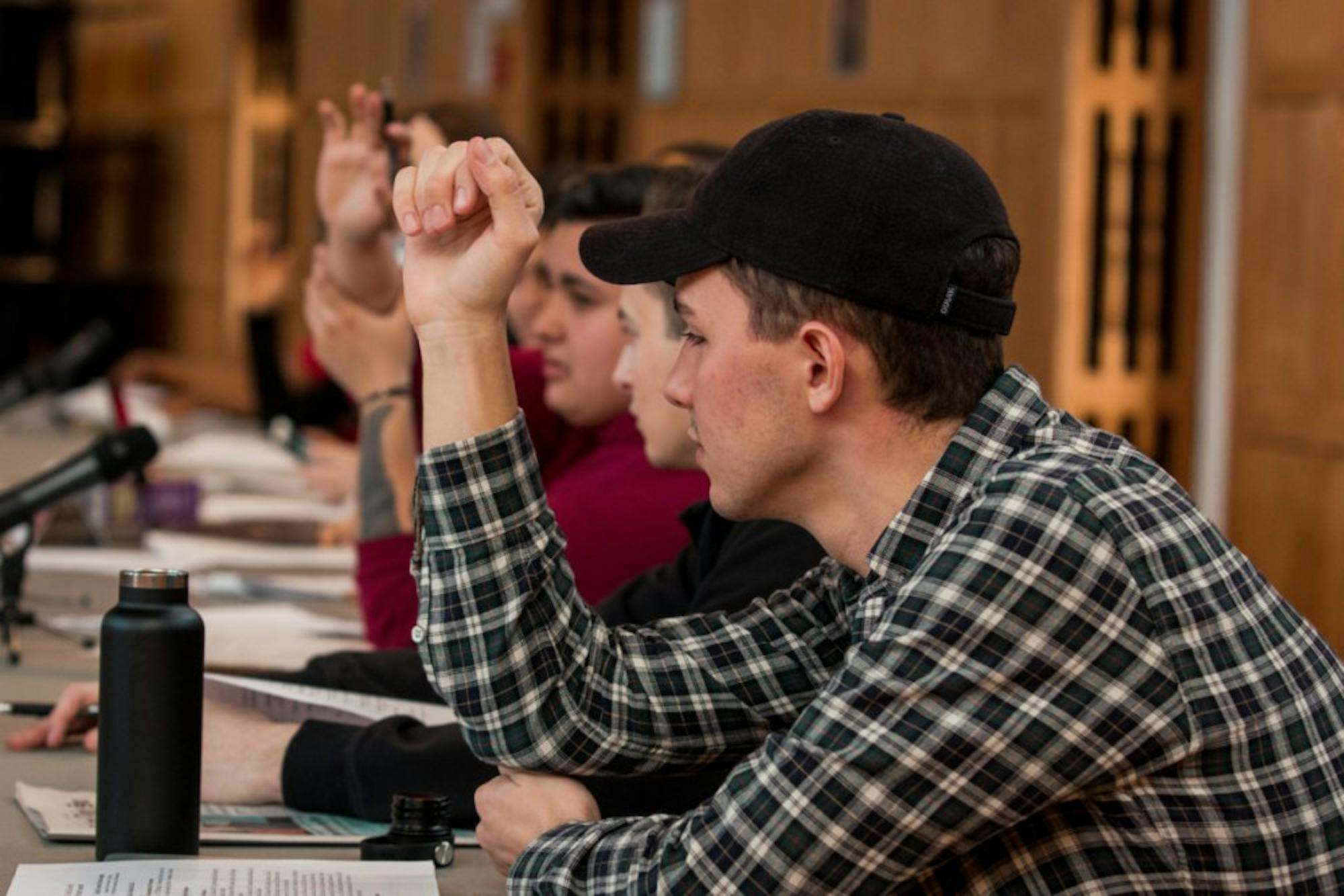 Student Assembly members raise their hands during the Thursday meeting in Willard Straight Hall. (Hannah Rosenberg/Sun Assistant Photography Editor)