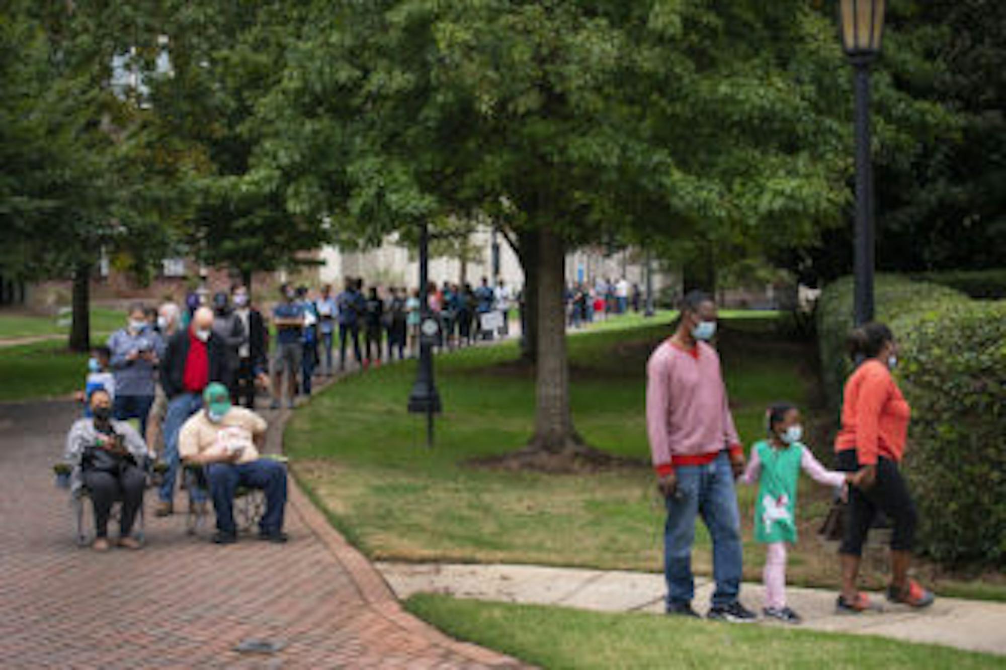 Voters stand and sit in line for early voting on Monday morning, Oct. 12, 2020, at Agnes Scott College in Decatur, Ga.