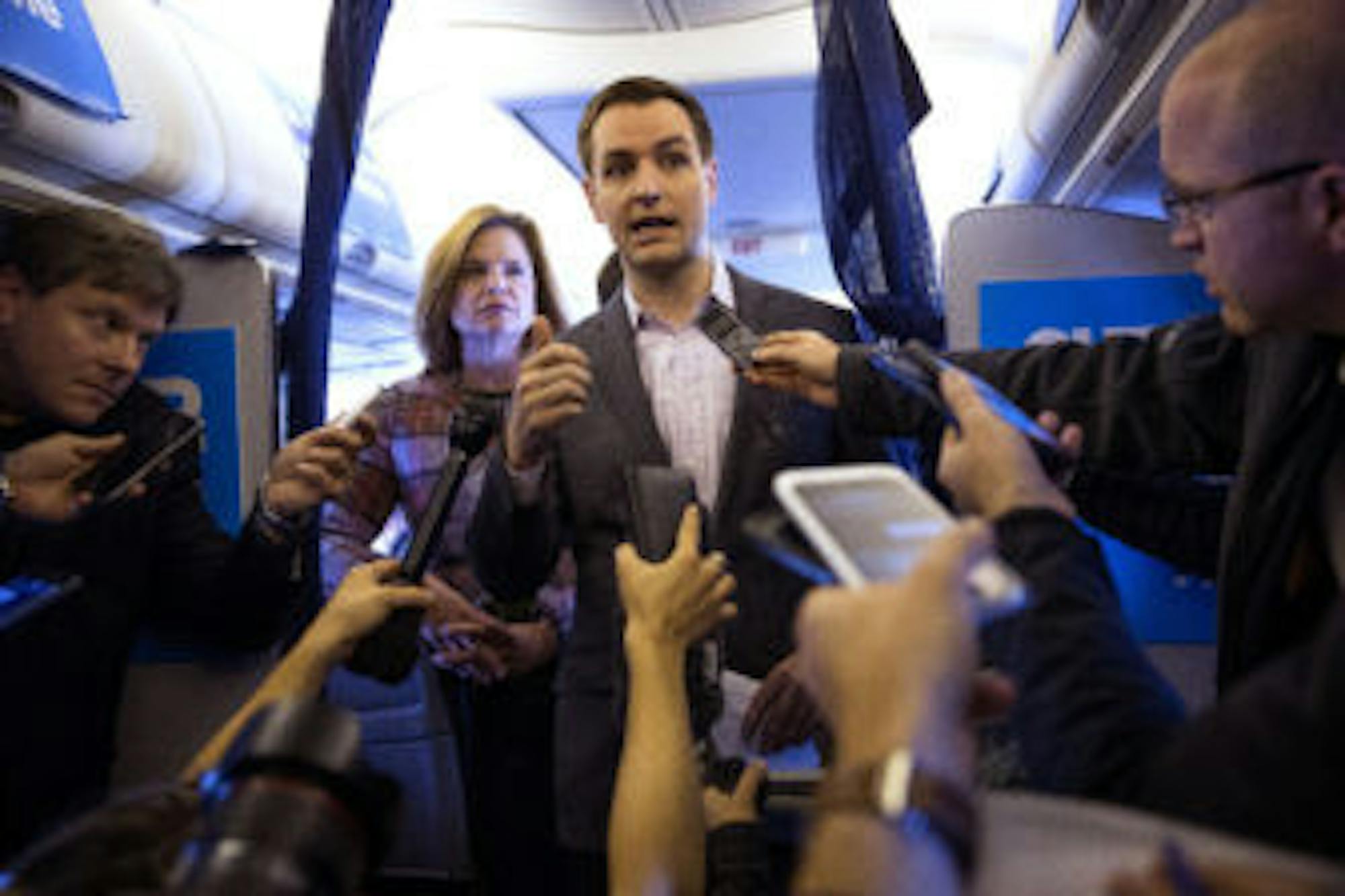 Robby Mook, presidential candidate Hillary Clinton's campaign manager, speaks to reporters on board the campaign plane in White Plains, N.Y., as it heads to Iowa for a rally, Oct. 28, 2016. James Comey, the director of the FBI, has alerted Congress of newly-uncovered emails that appear to be pertinent to the closed investigation of whether then-Secretary of State Clinton or her aides had mishandled classified information. Behind Mook is Jennifer Palmieri, communications director.