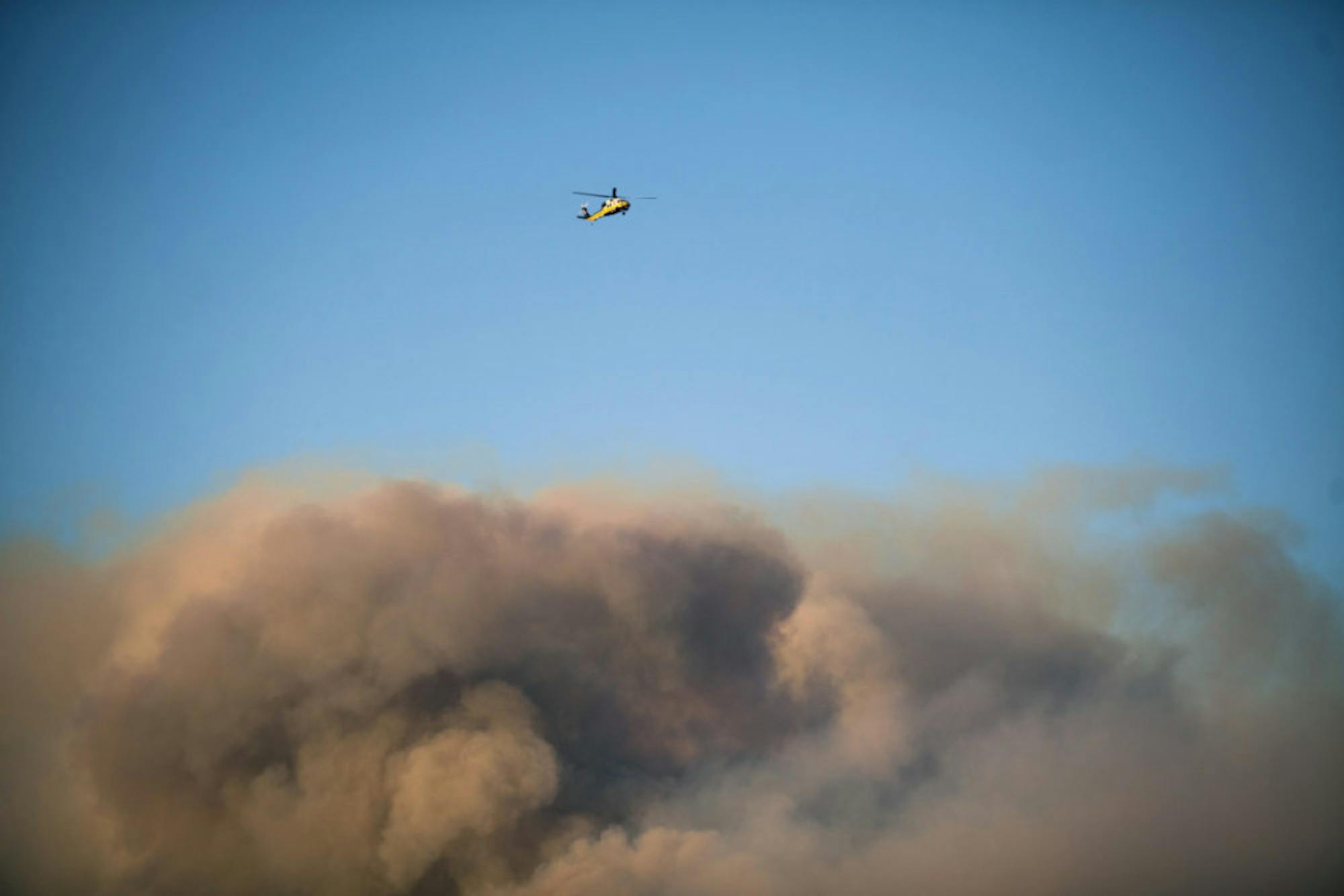 A helicopter flies above the roiling smoke from the Woolsey Fire near Thousand Oaks, Calif., on Nov. 9.
