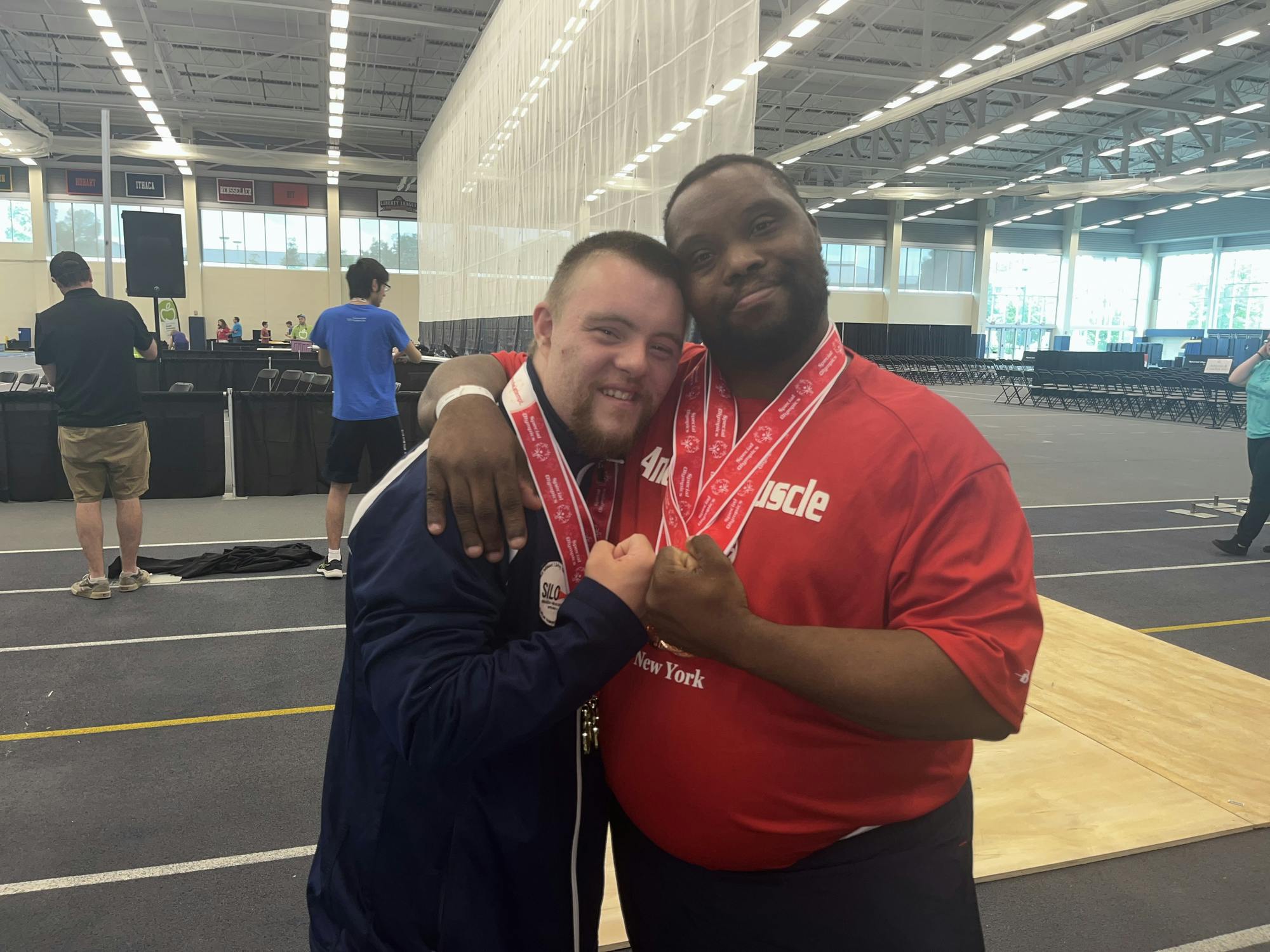Joey Collins (left) and Daniel Fletcher (right) hug after receiving their medals for powerlifting.