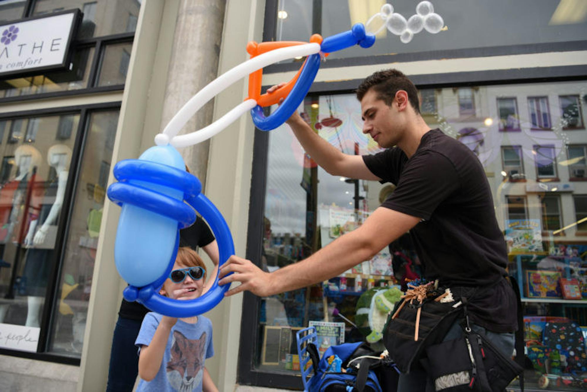 Balloon twister and magician Brandon Axelrod fashions a scuba diving tank out of balloons for a child at the C.U. Downtown event on Saturday.