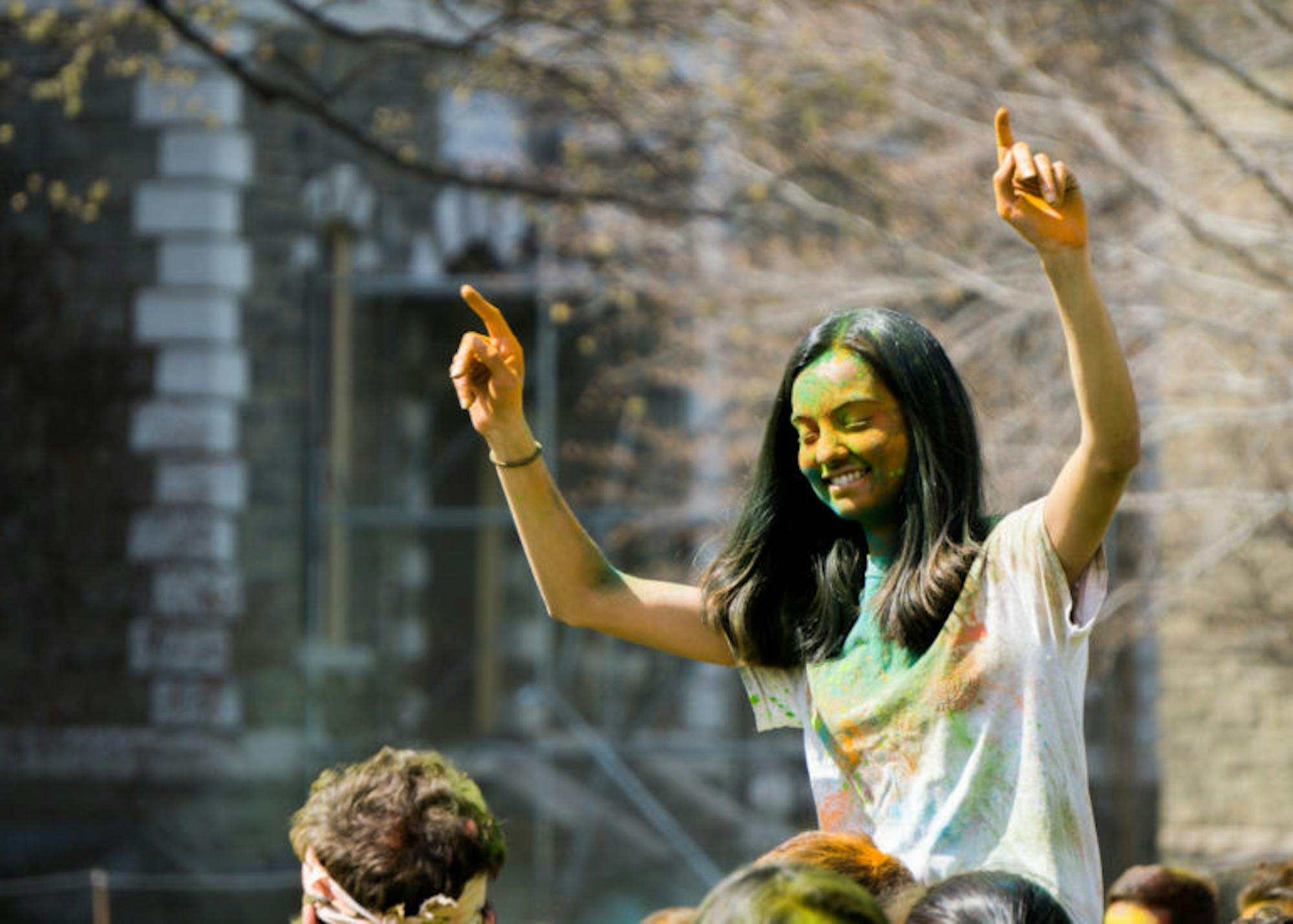 A student rides on the shoulders of a classmate during the Holi celebration at the Arts Quad on Saturday.