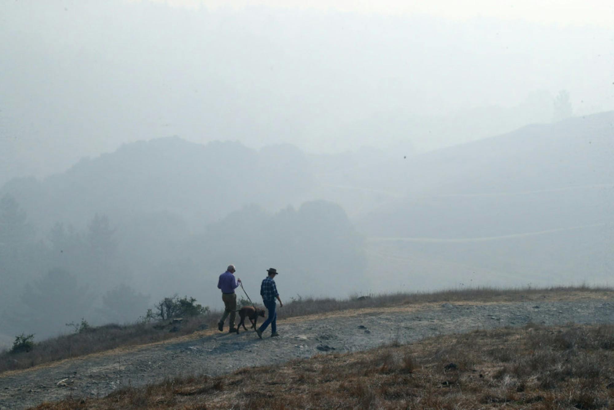 Smoke from the Camp Fire lingers over Oakland Hills as people walk their dog in Oakland, California on Nov. 15.