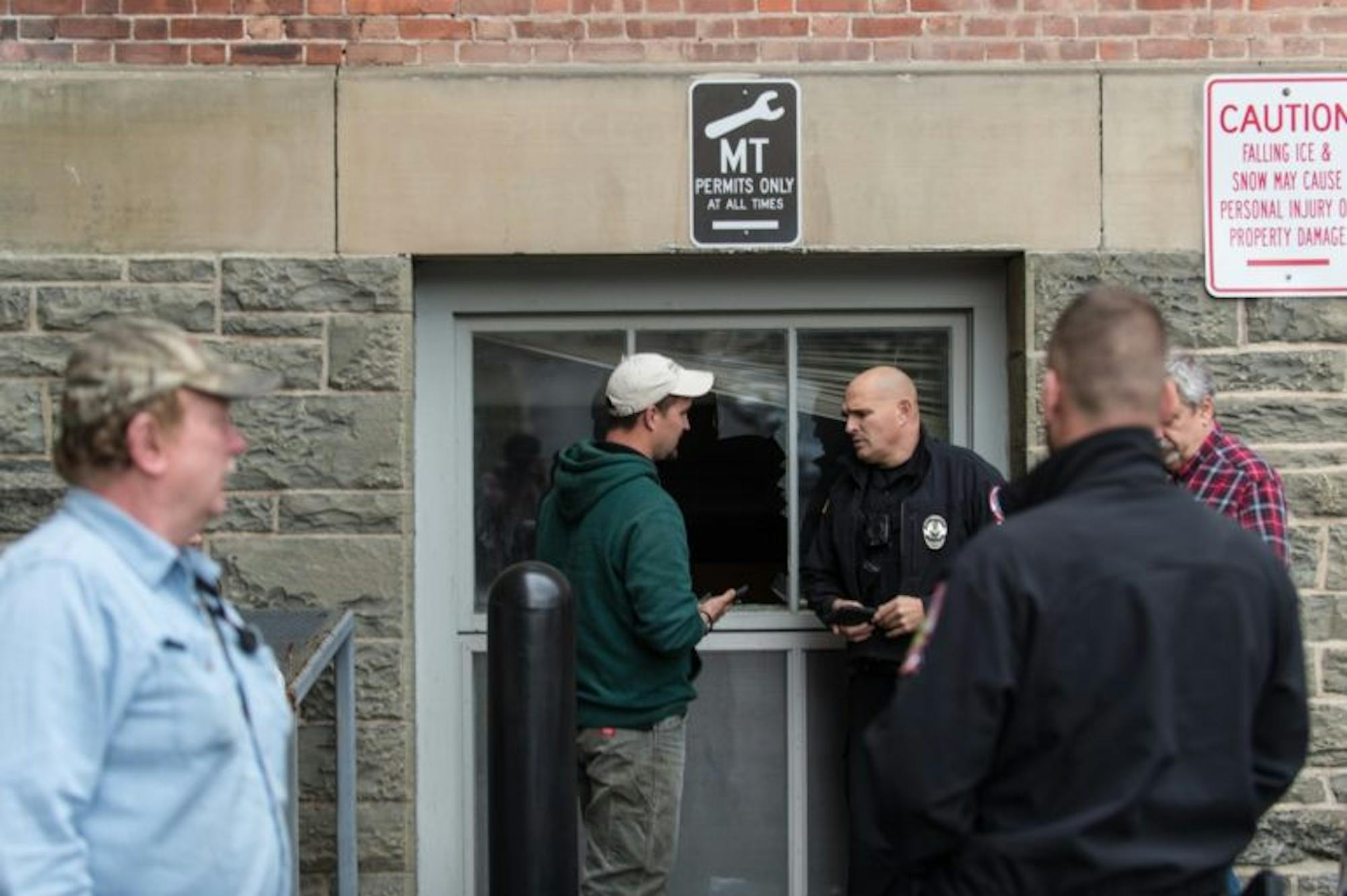 An animal control employee and Cornell Police stand next to the window in Rockefeller Hall that a deer jumped through on Thursday, waiting for a environmental conservation officer to arrive.