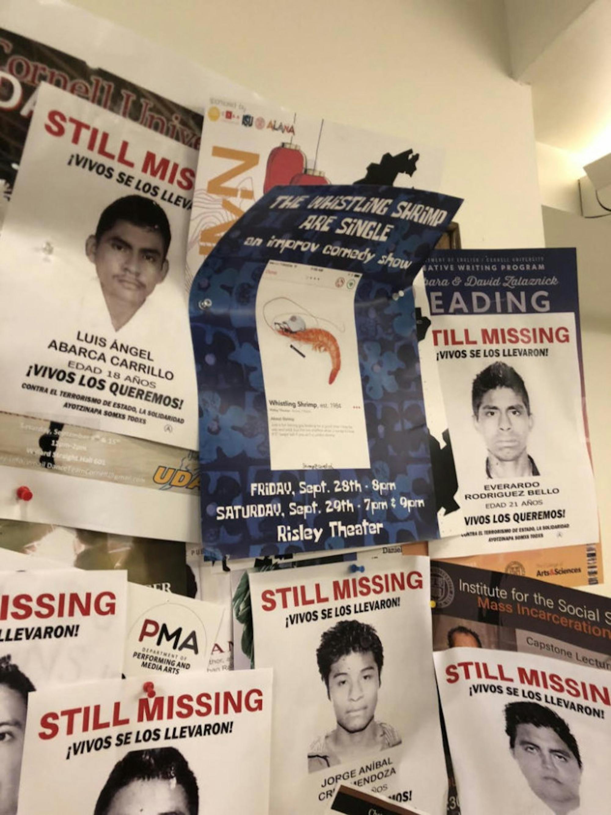 A member of The Whistling Shrimp moved one of MEChA de Cornell's fliers so their own flier could be visible on the bulletin board.