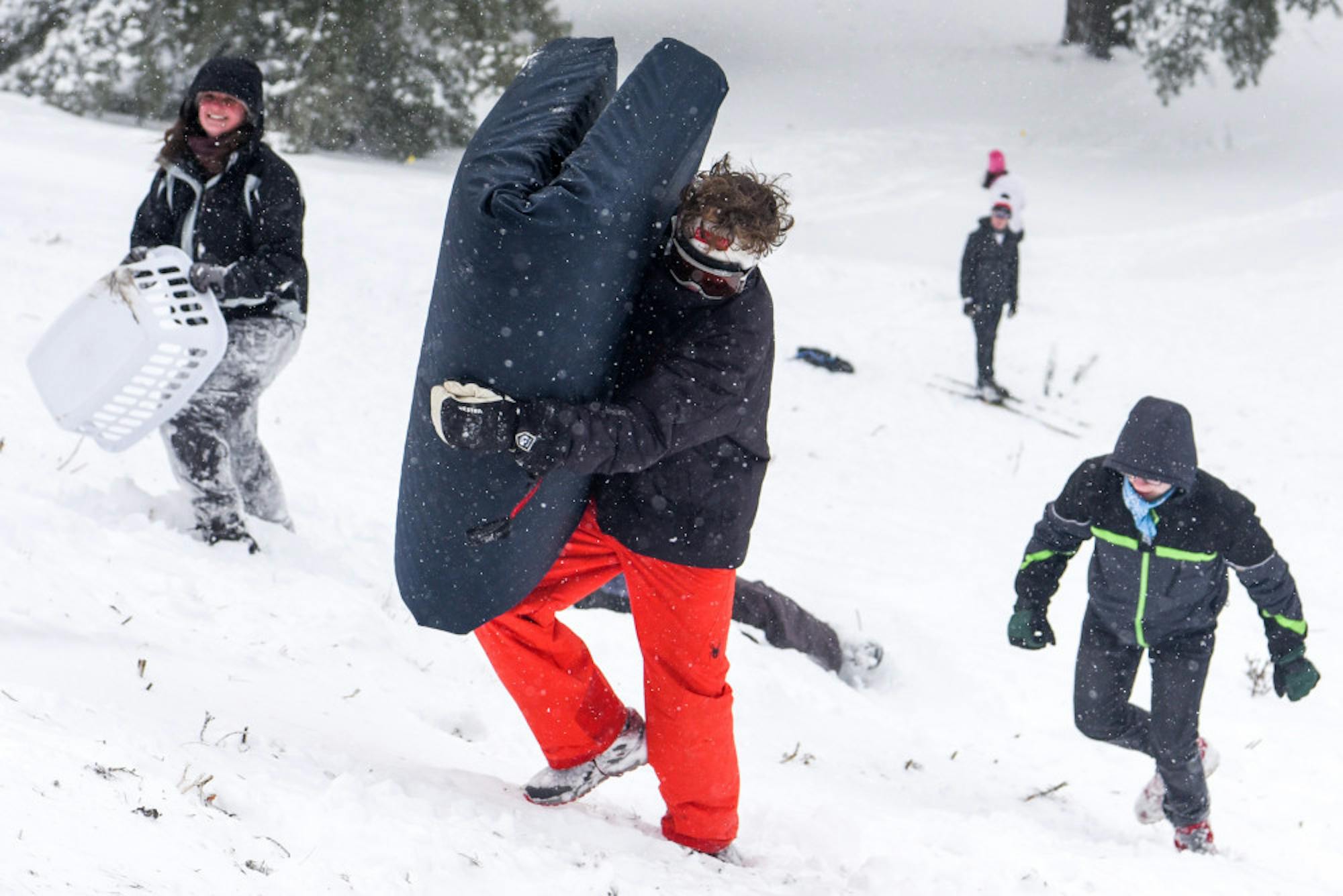 A student climbs up Libe Slope with a mattress while another carries a laundry basket during the snow day on Friday. (Boris Tsang/Sun Photography Editor)