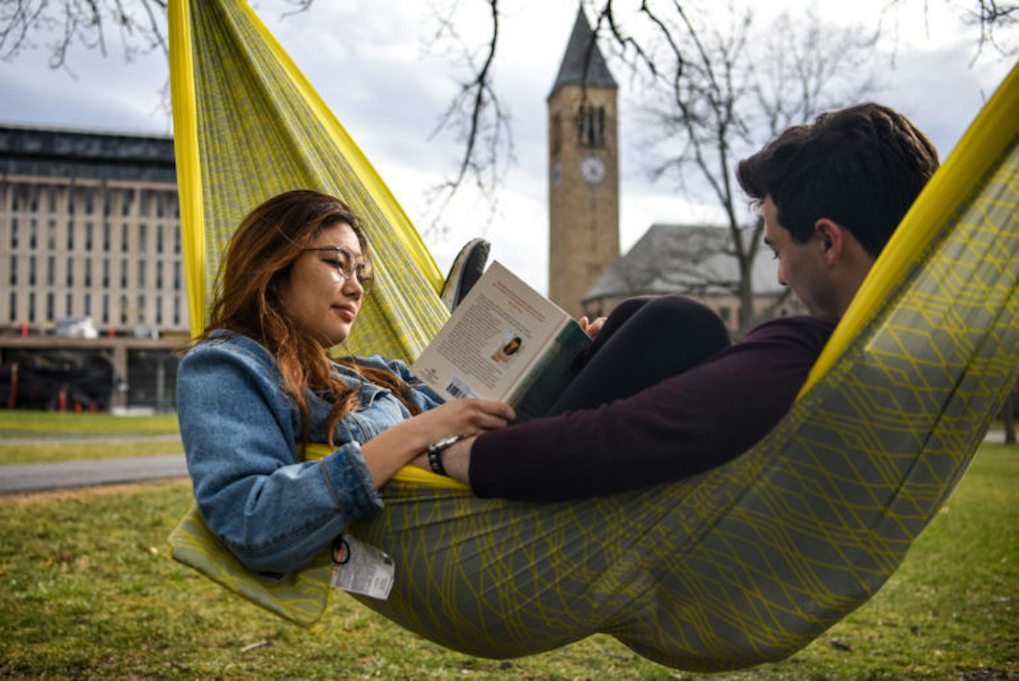 Kelly Song '20, left, and Nick Diaco '21 read in a hammock on the Arts Quad on Friday, as McGraw Tower poked up behind them. After scattered thunderstorms in the morning, temperatures peaked in the 60s in the afternoon, the nice weather inviting students to lounge outside. (Boris Tsang/Sun Photography Editor)