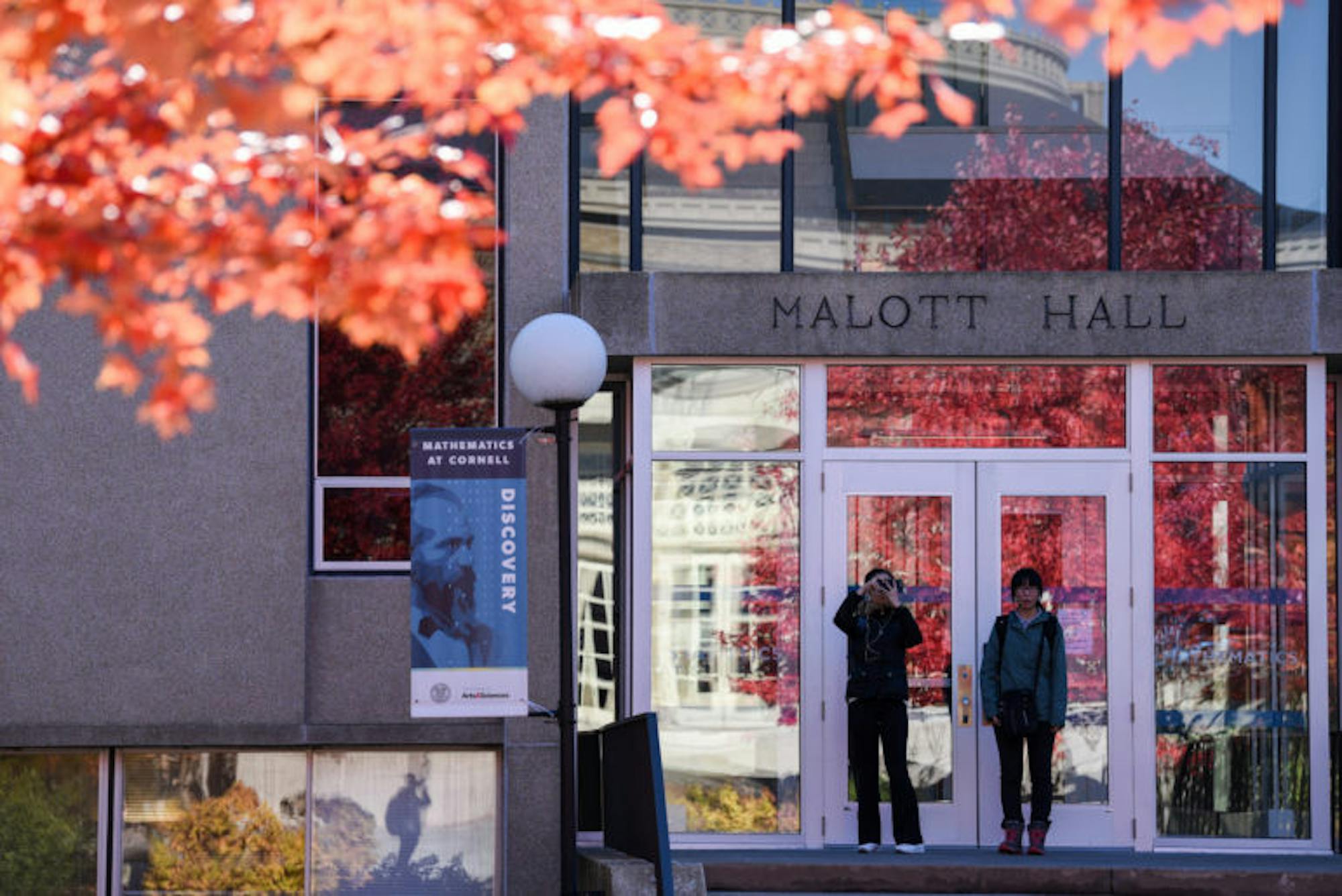 Students stop to admire the red leaves in front of Bailey Hall on Tuesday. (Boris Tsang / Sun Assistant Photography Editor)