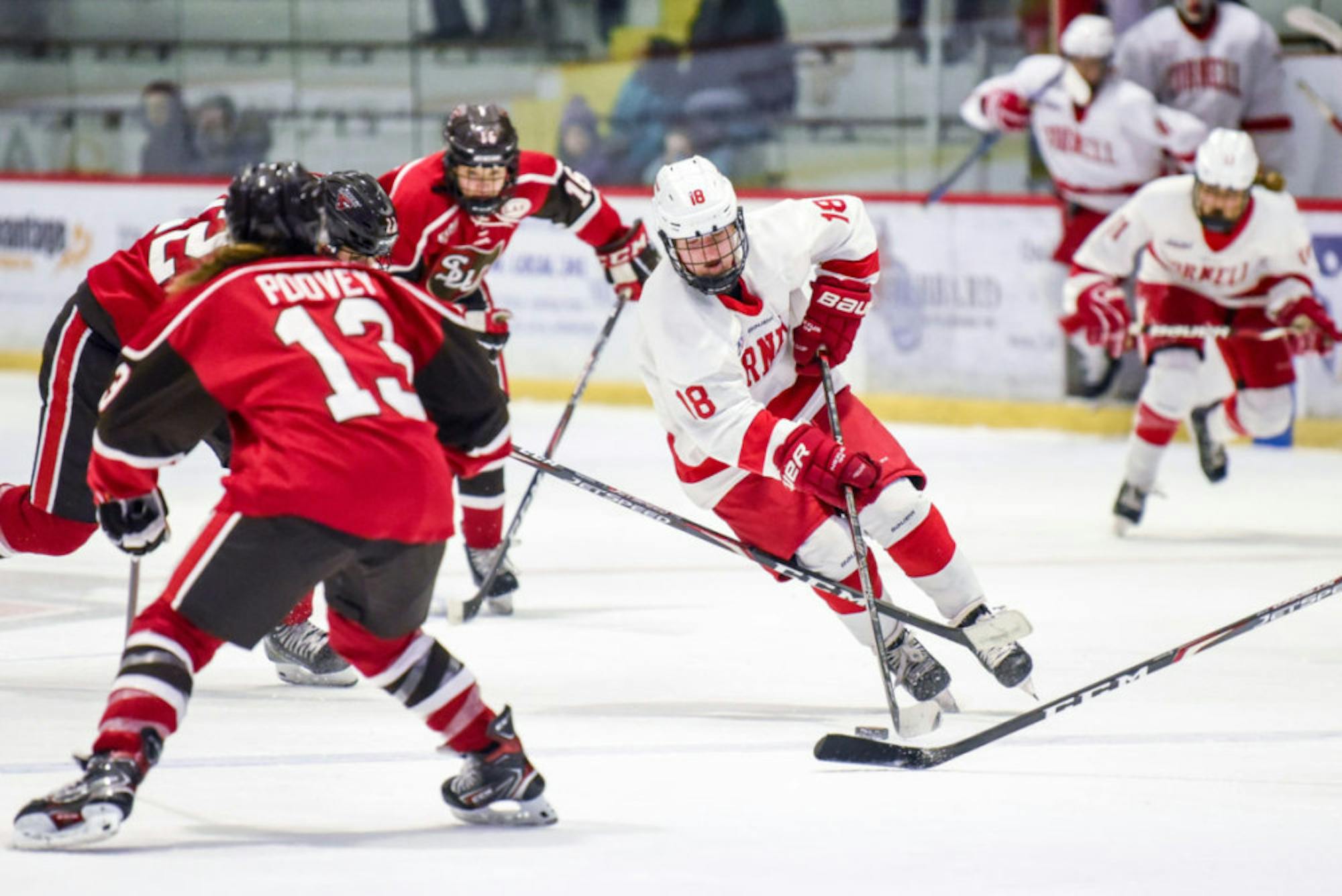 Senior forward Paige Lewis navigates the puck between St. Lawrence players on Saturday. After a tie for most of the game, the women's hockey team took home the 3-2 win. (Boris Tsang/Sun Photography Editor)