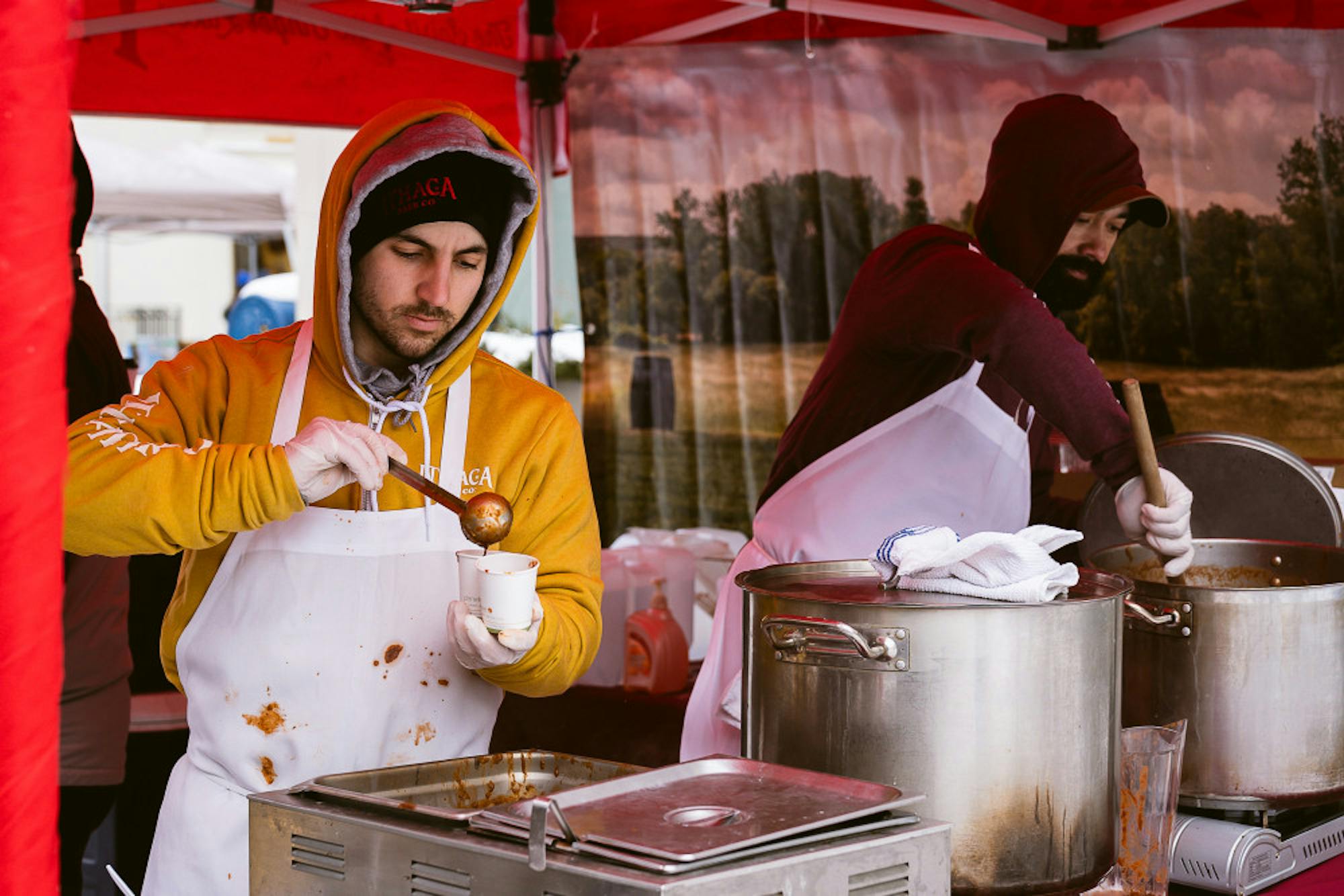Ithaca Beer Co. employees scoop chili into sample cups at the 22nd annual Chili Cook-Off in the Ithaca Commons. On Saturday the family-friendly festival attracted more than 30 restaurants ready to compete for the ultimate chili recipe. (Ashley He/Sun Staff Photographer)