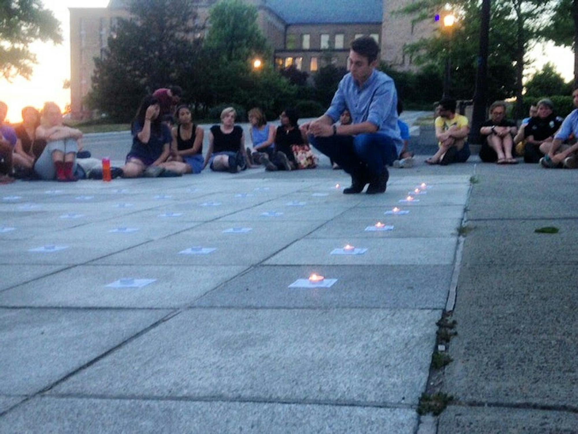 Joshua Goddard ’18, one of the event's organizers, lights one of 49 candles, each honoring one victim killed in the shooting.